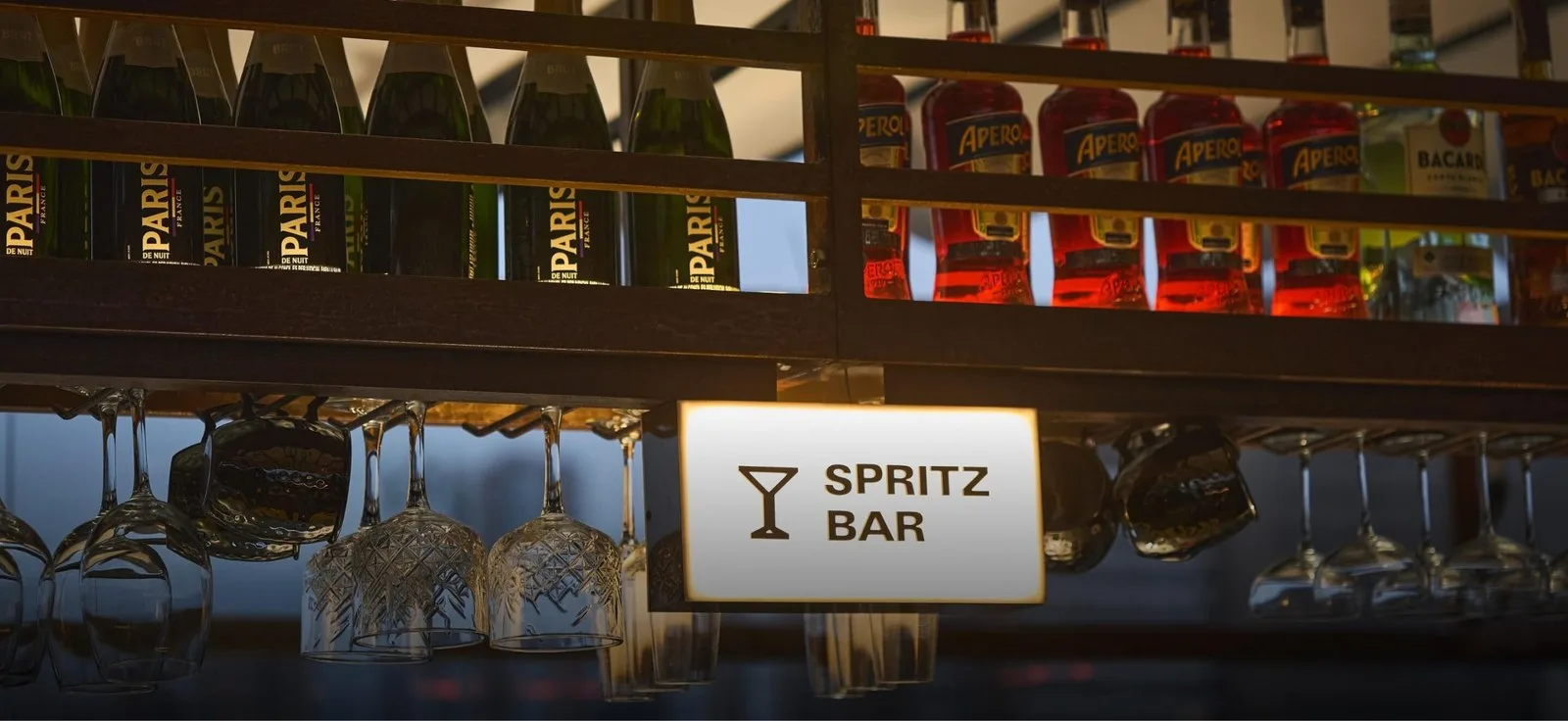Barra de spritz de The Terrace con botellas y copas colgadas
